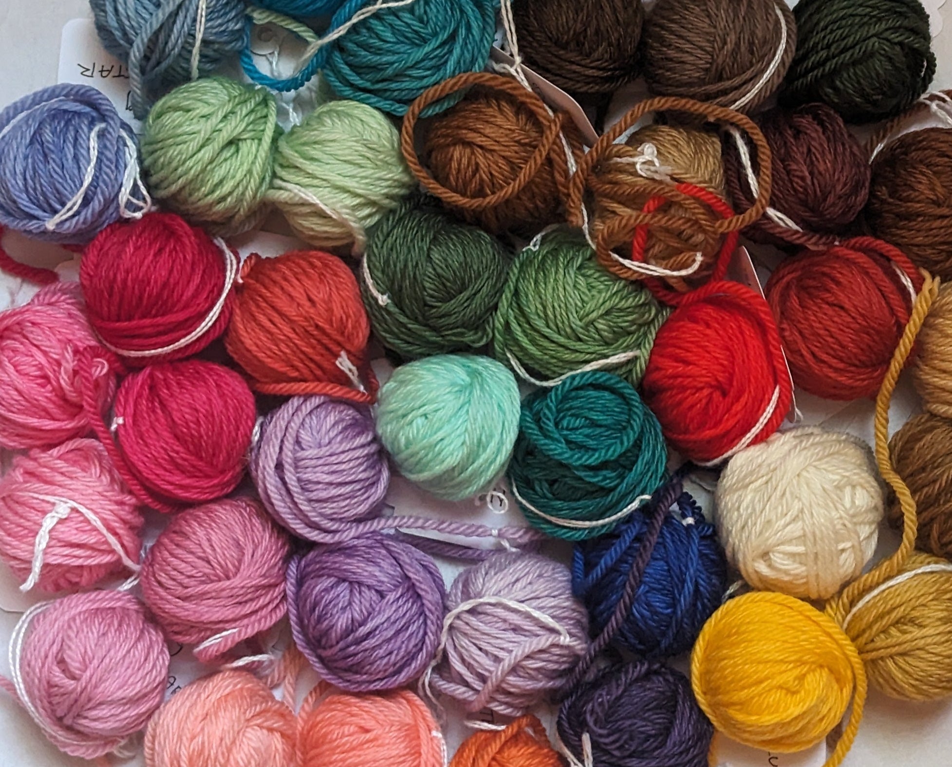 Assorted colorful yarn balls arranged in a circular pattern on a white background